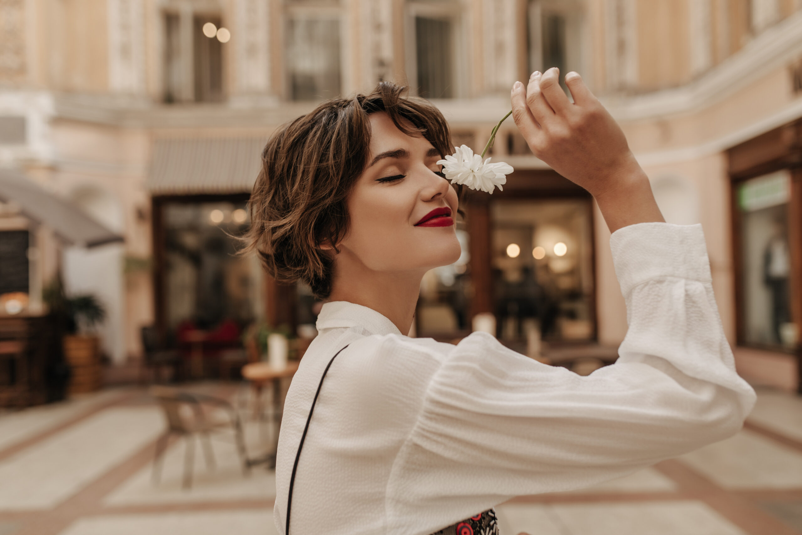 Can Women Wear Oud Perfume? Everything You Need To Know 1 lovely woman white shirt with long sleeve holding flower city short haired woman with red lipstick posing street scaled